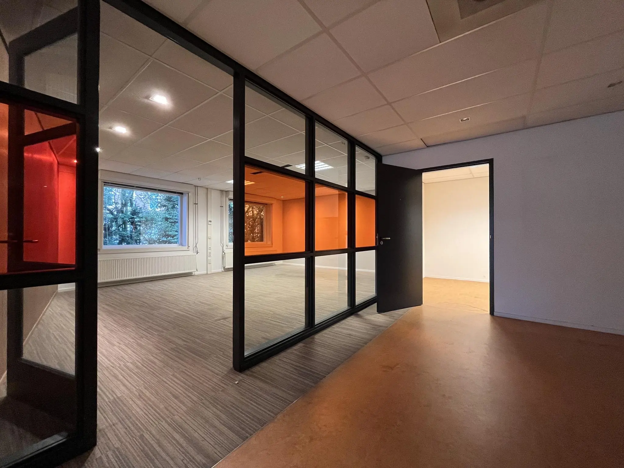 Modern kantoorinterieur aan de 2e Daalsedijk met glazen wanden, gekleurde accenten en uitzicht op groen buitengebied.